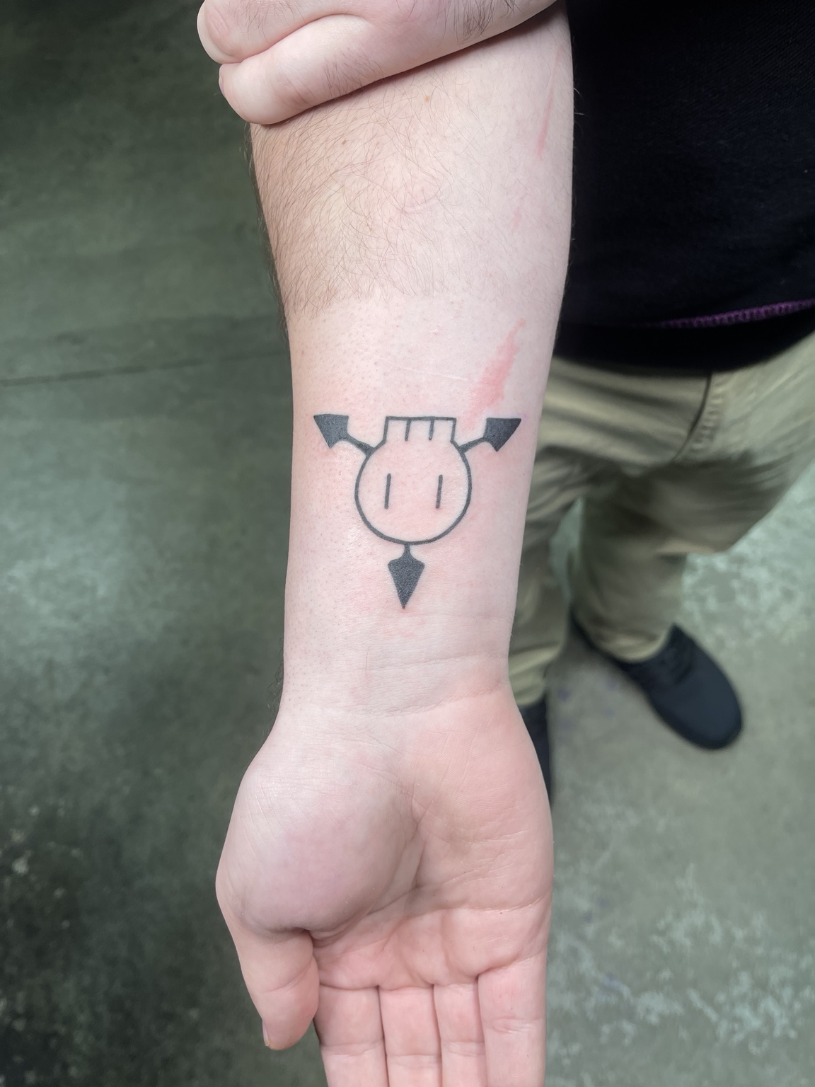 Small black forearm symbol tattoo