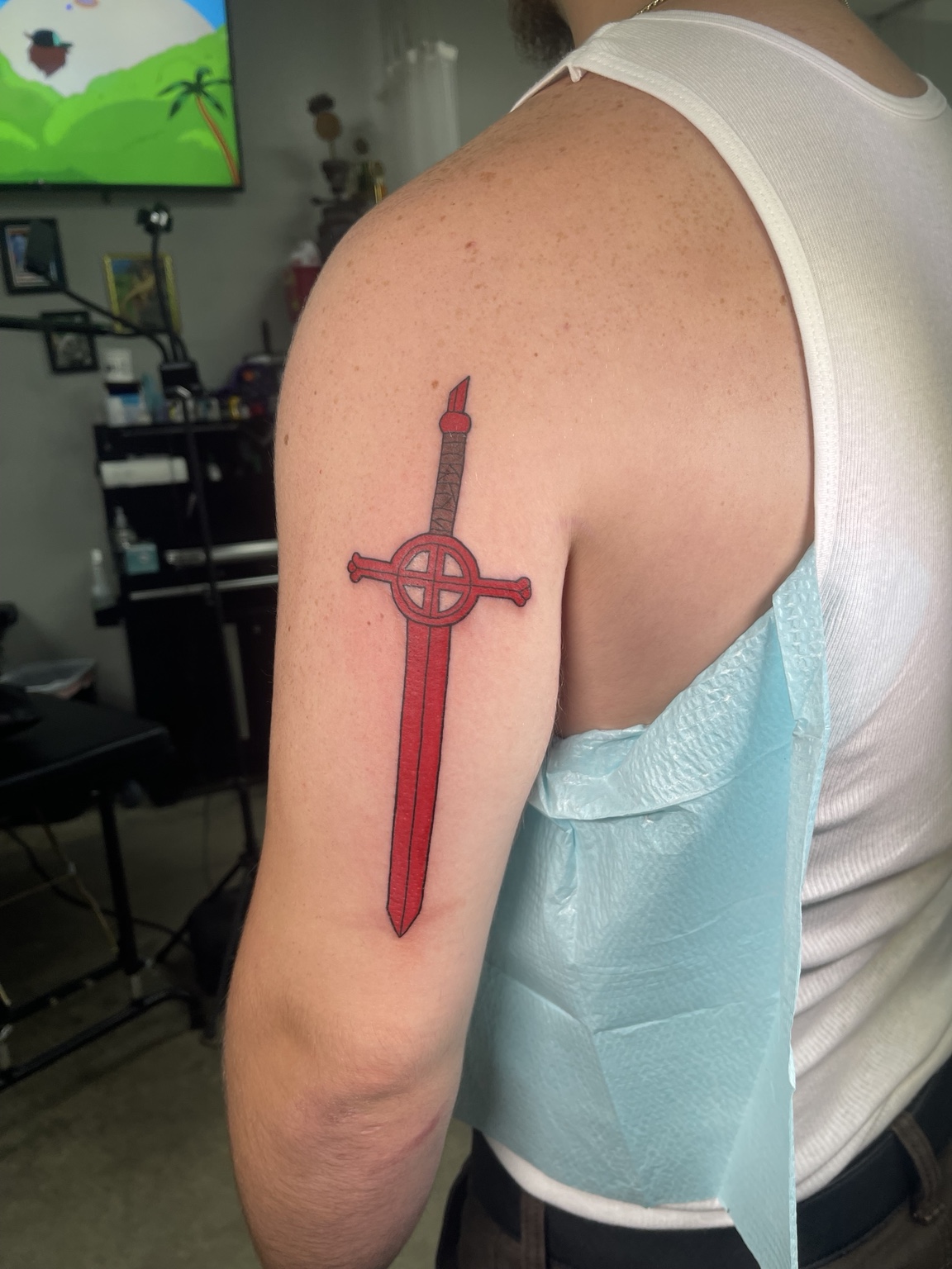 Red sword upper arm tattoo