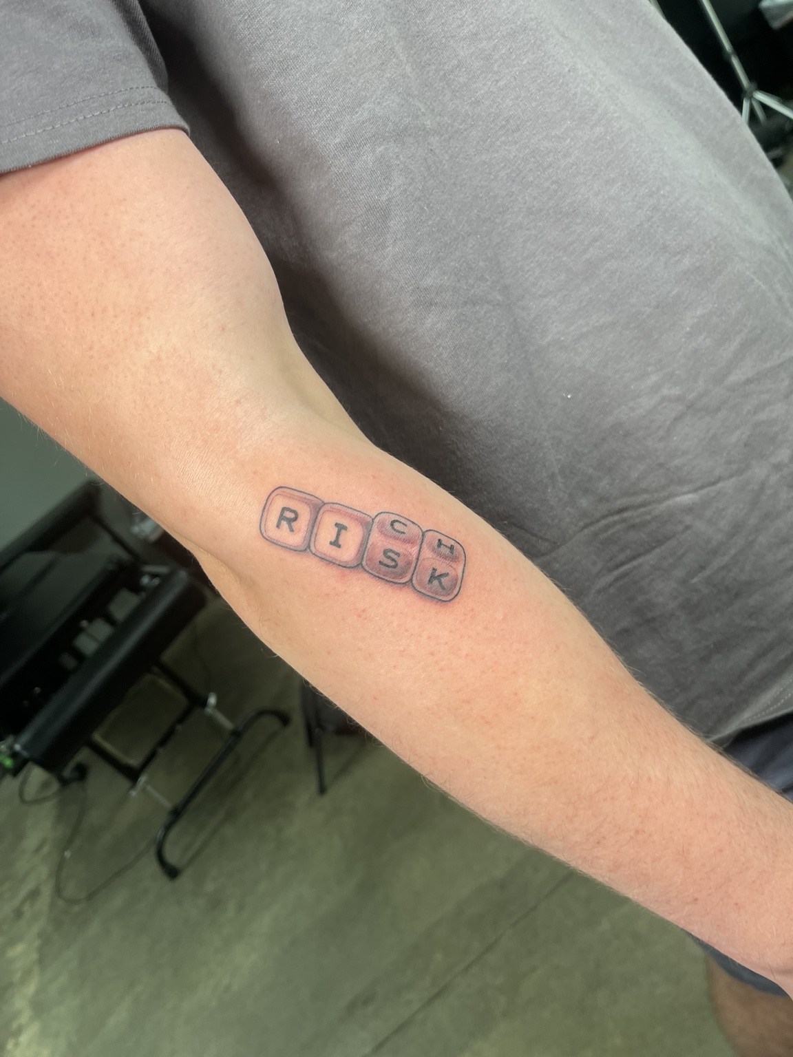 Small block-letter tattoo reading RISE